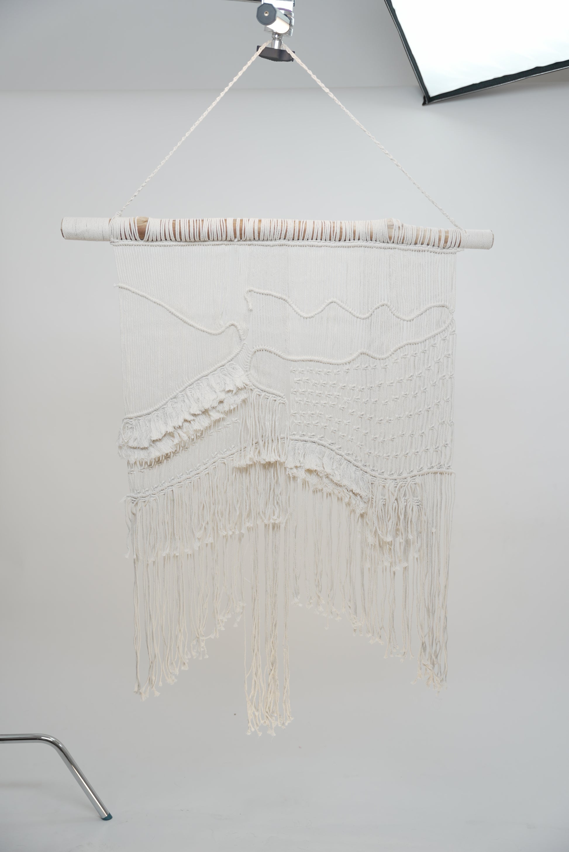 The macrame wall hanger photographed against a neutral background showcasing the design