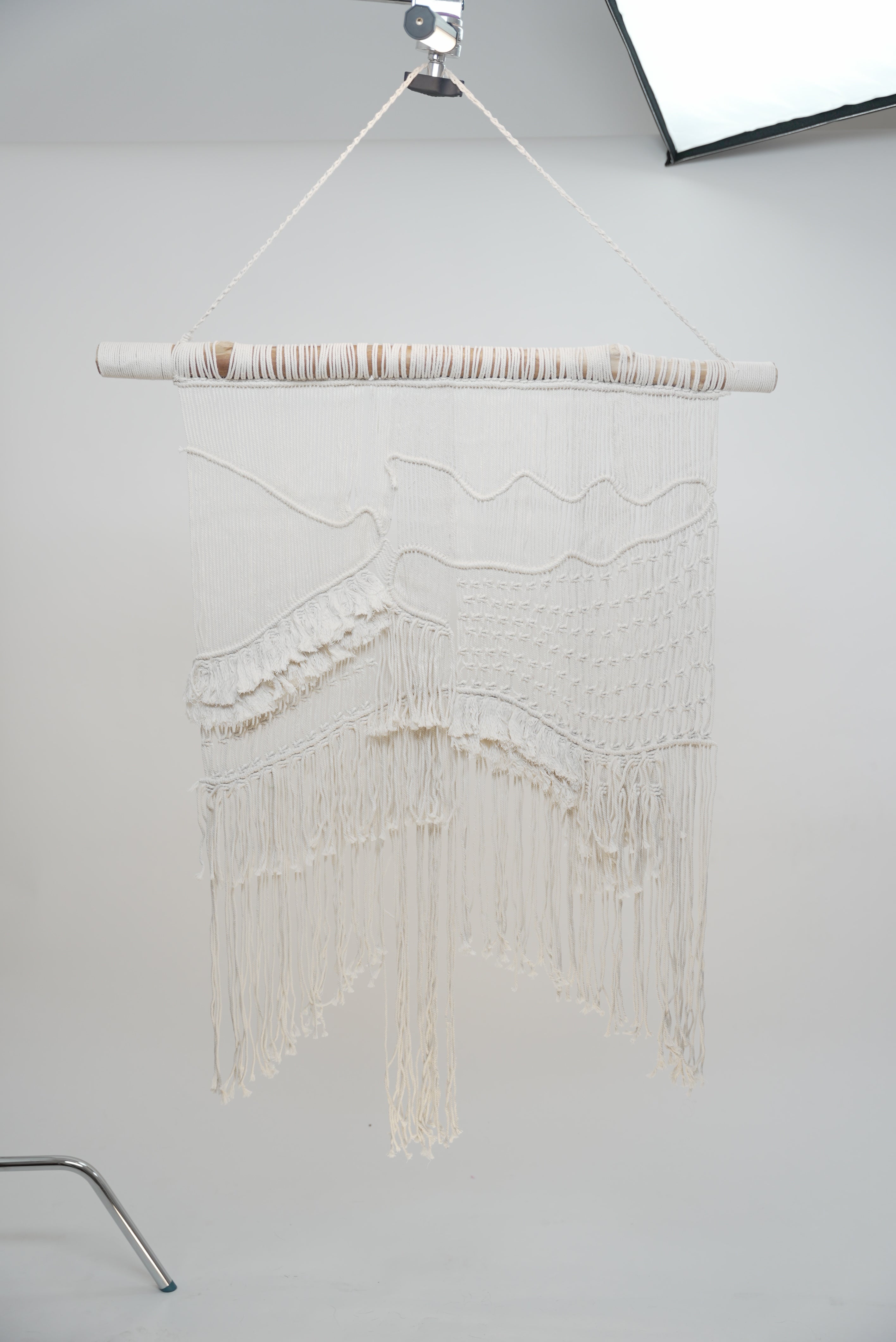 The macrame wall hanger photographed against a neutral background showcasing the design