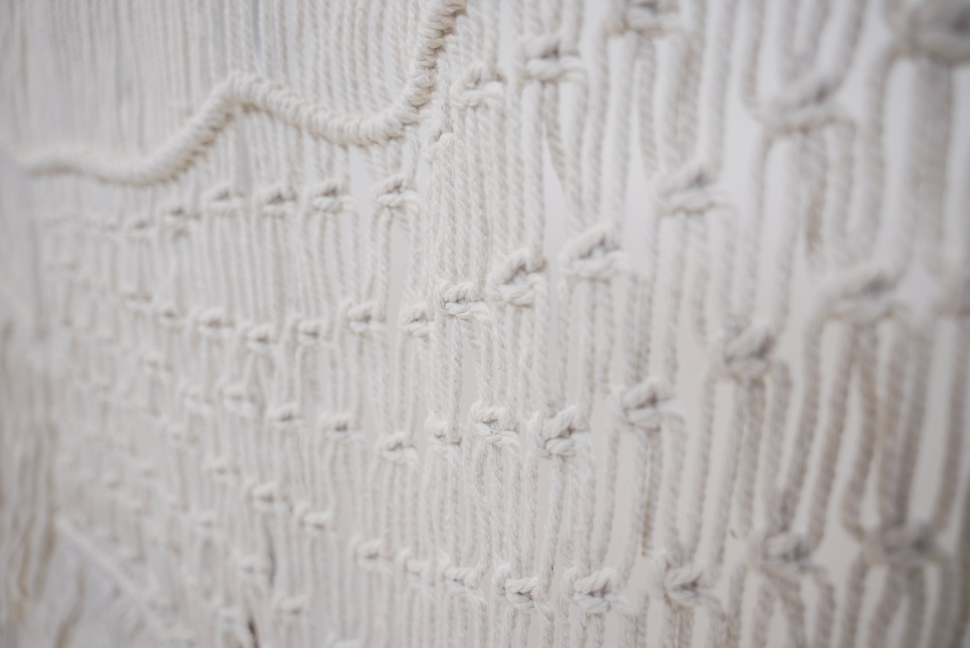Close-up of the macrame wall hanger photographed against a neutral background showcasing the design