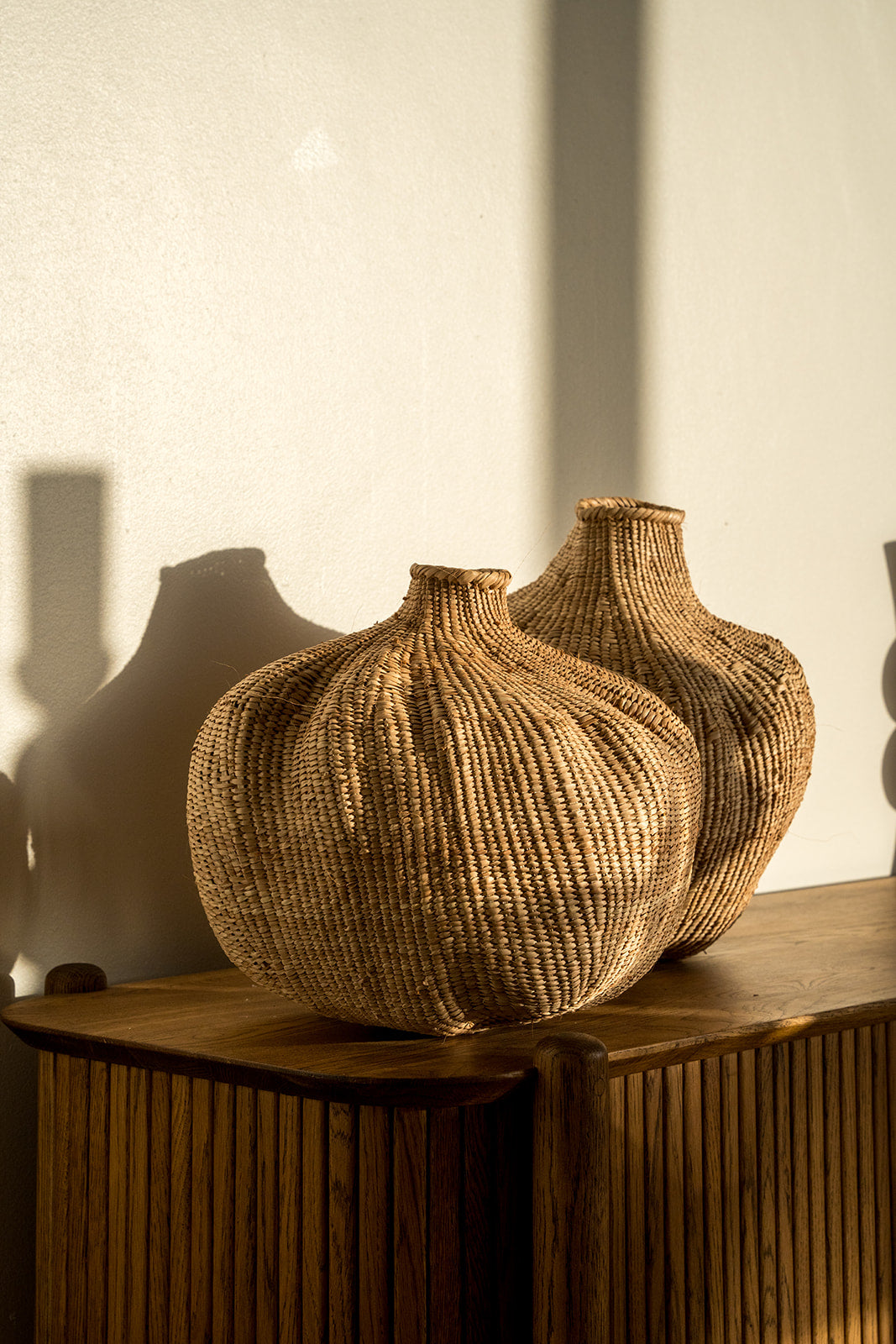 Two of the garlic gourds photographed on a side table with afternoon sun on them