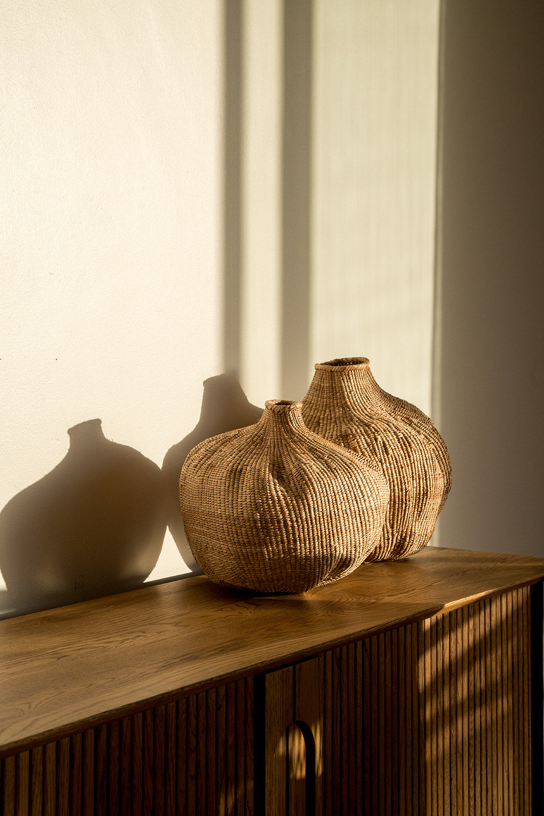 Two of the garlic gourds photographed on a side table with afternoon sun on them