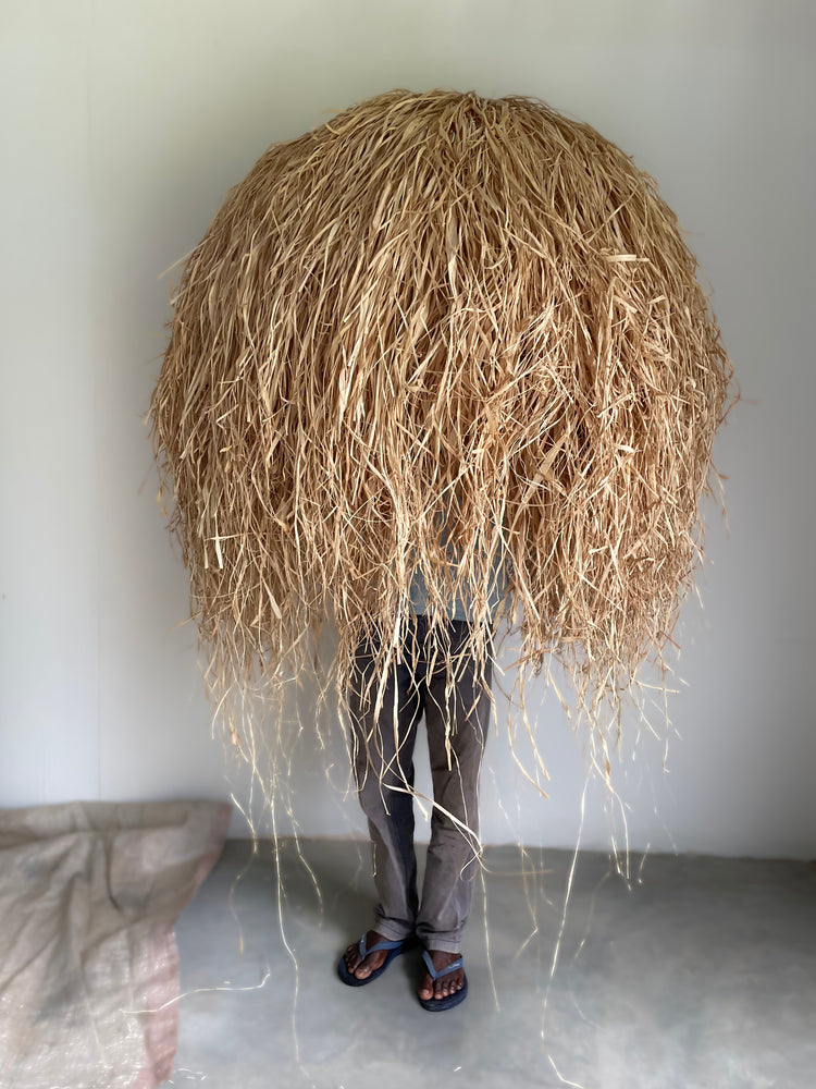 Bush Baby Dome Raffia Pendants on display with a man holding it for size