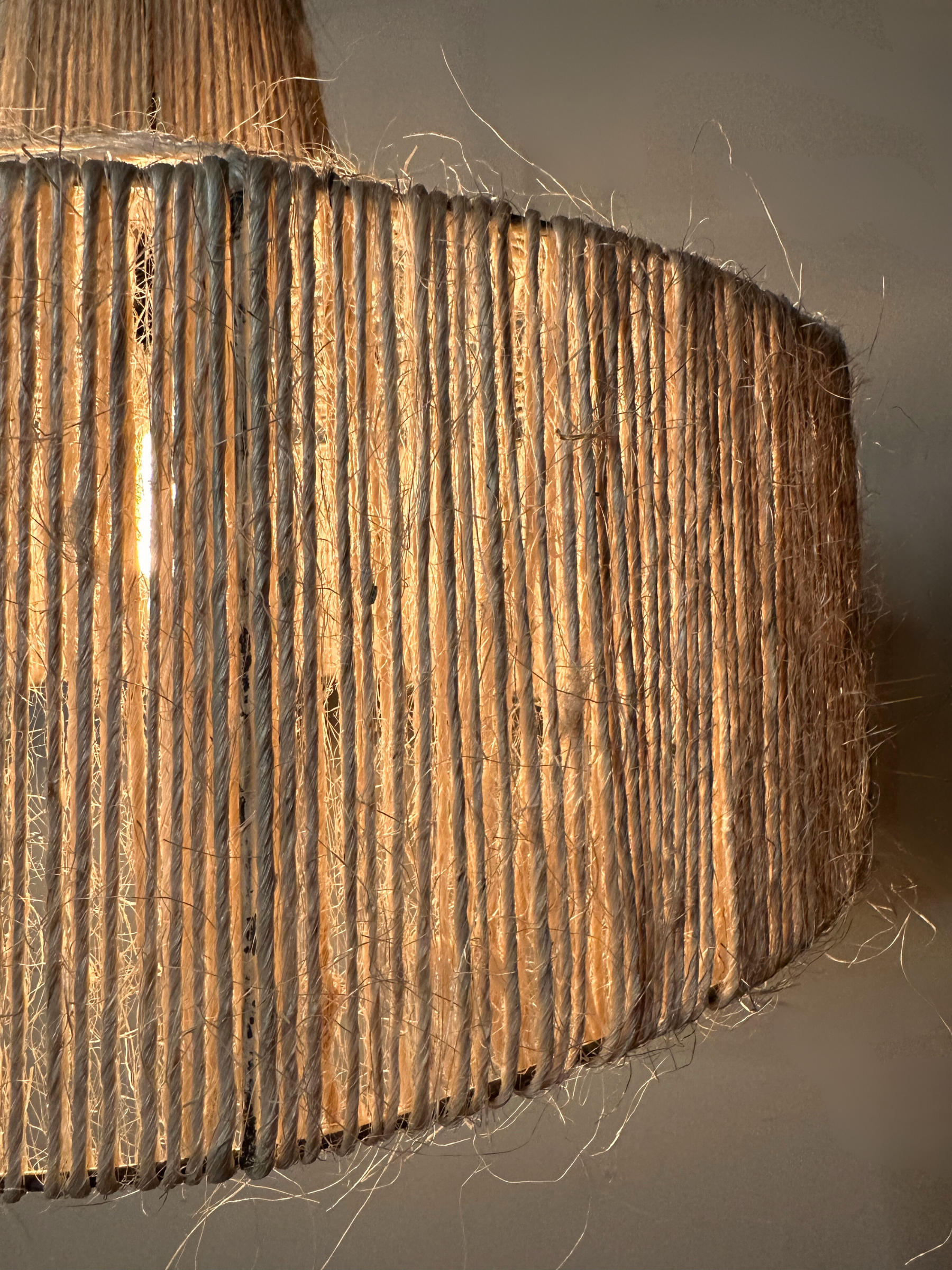 Close up of the Sisal pendant powered on in front of a wall