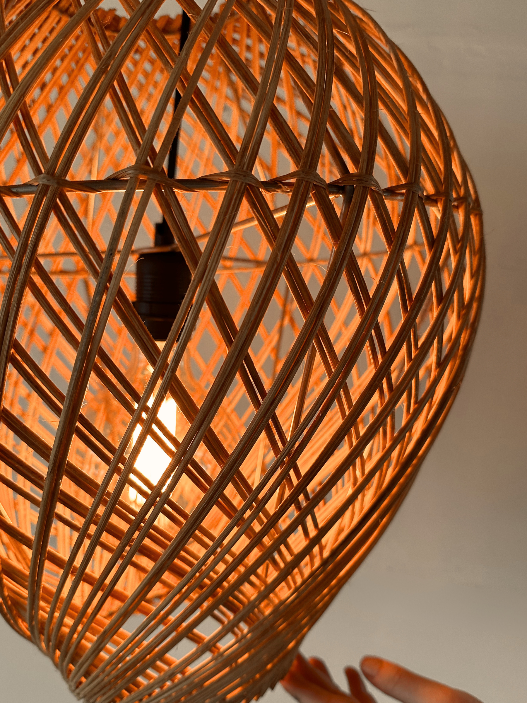 Locally handwoven rattan pendant light with a warm glow up close