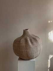 The garlic gourd photographed on a pedestal against a neutral wall