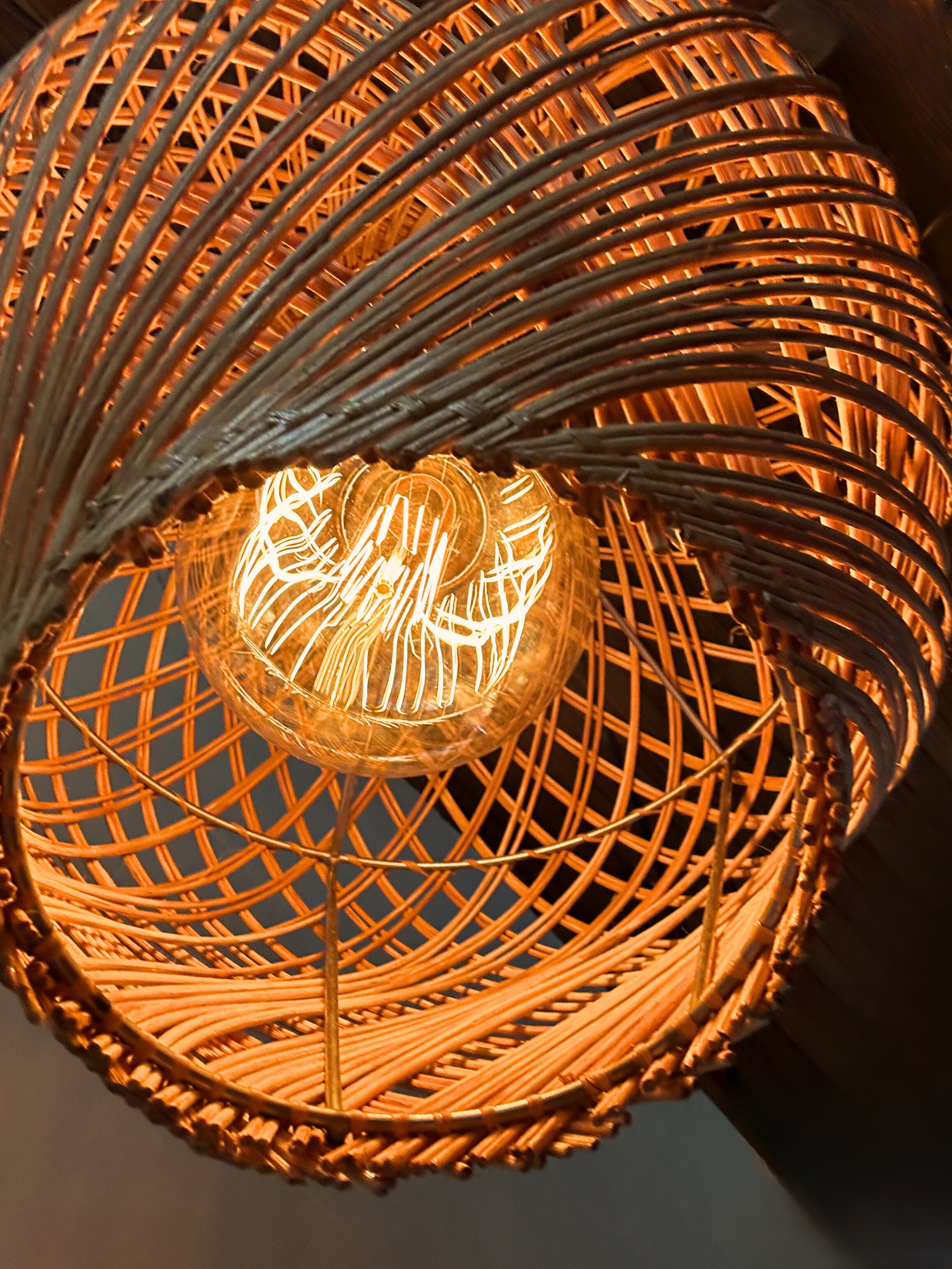 Locally handwoven rattan pendant light with a warm glow, from below