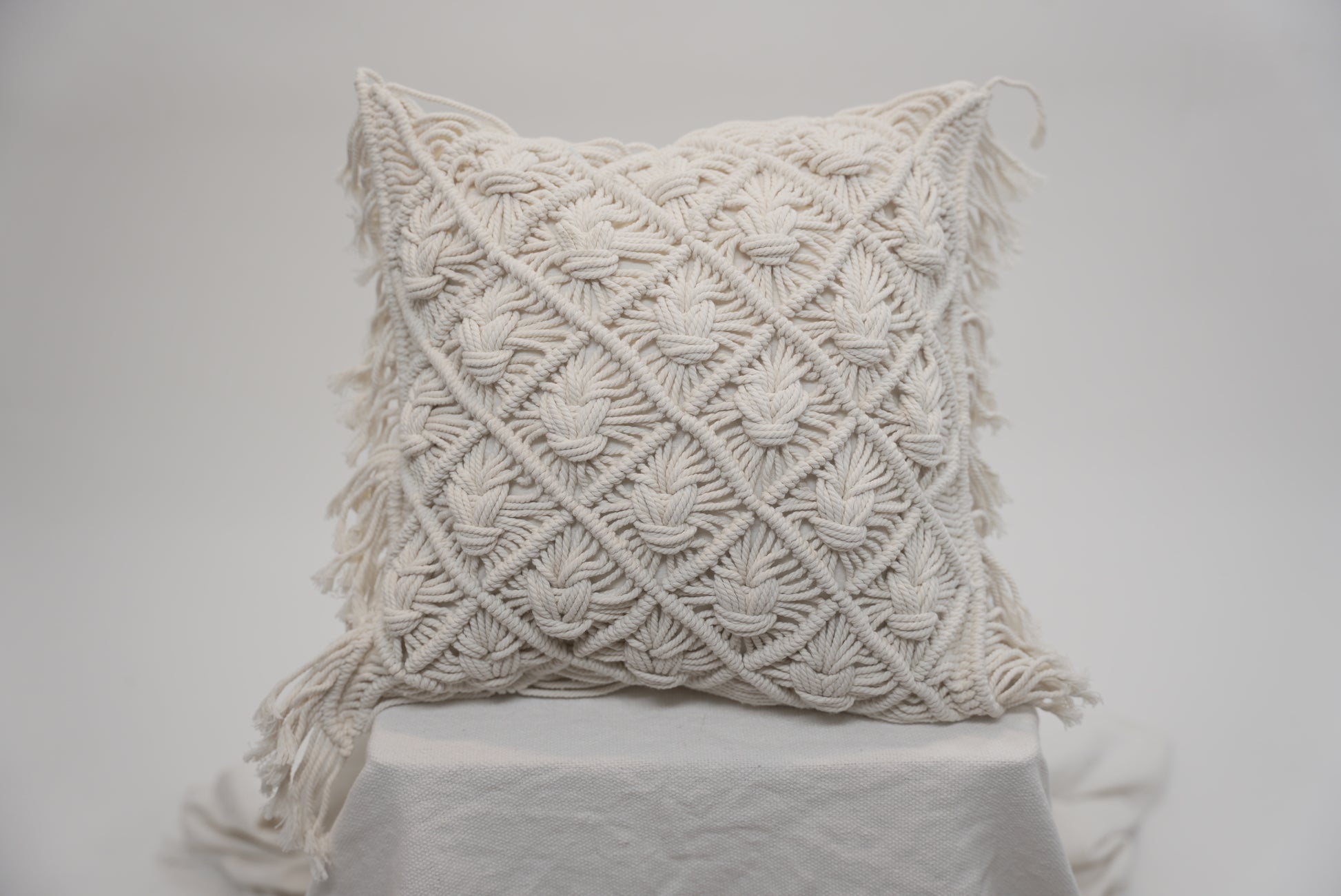 The macrame scatter cushions photographed against a neutral background