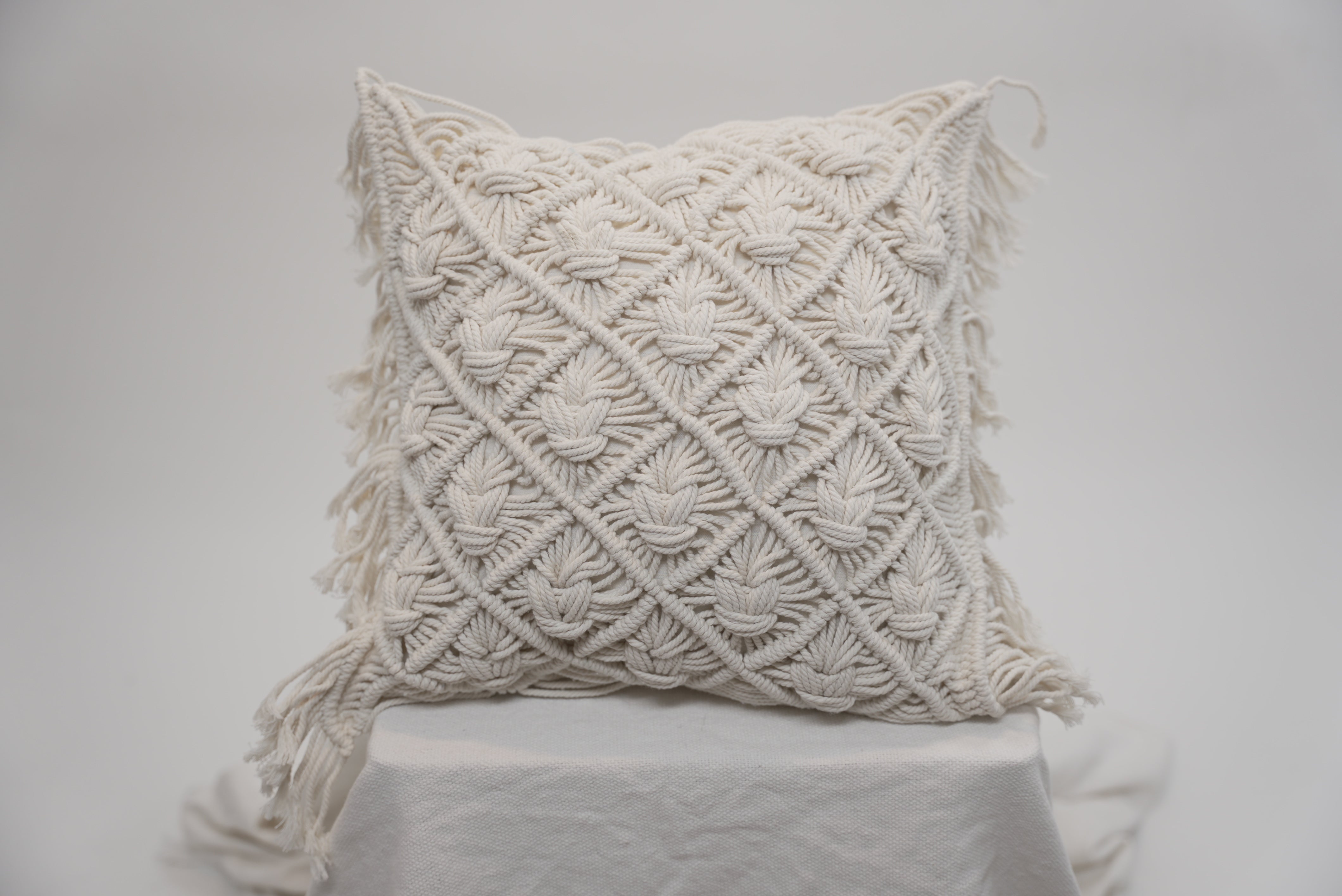 The macrame scatter cushions photographed against a neutral background