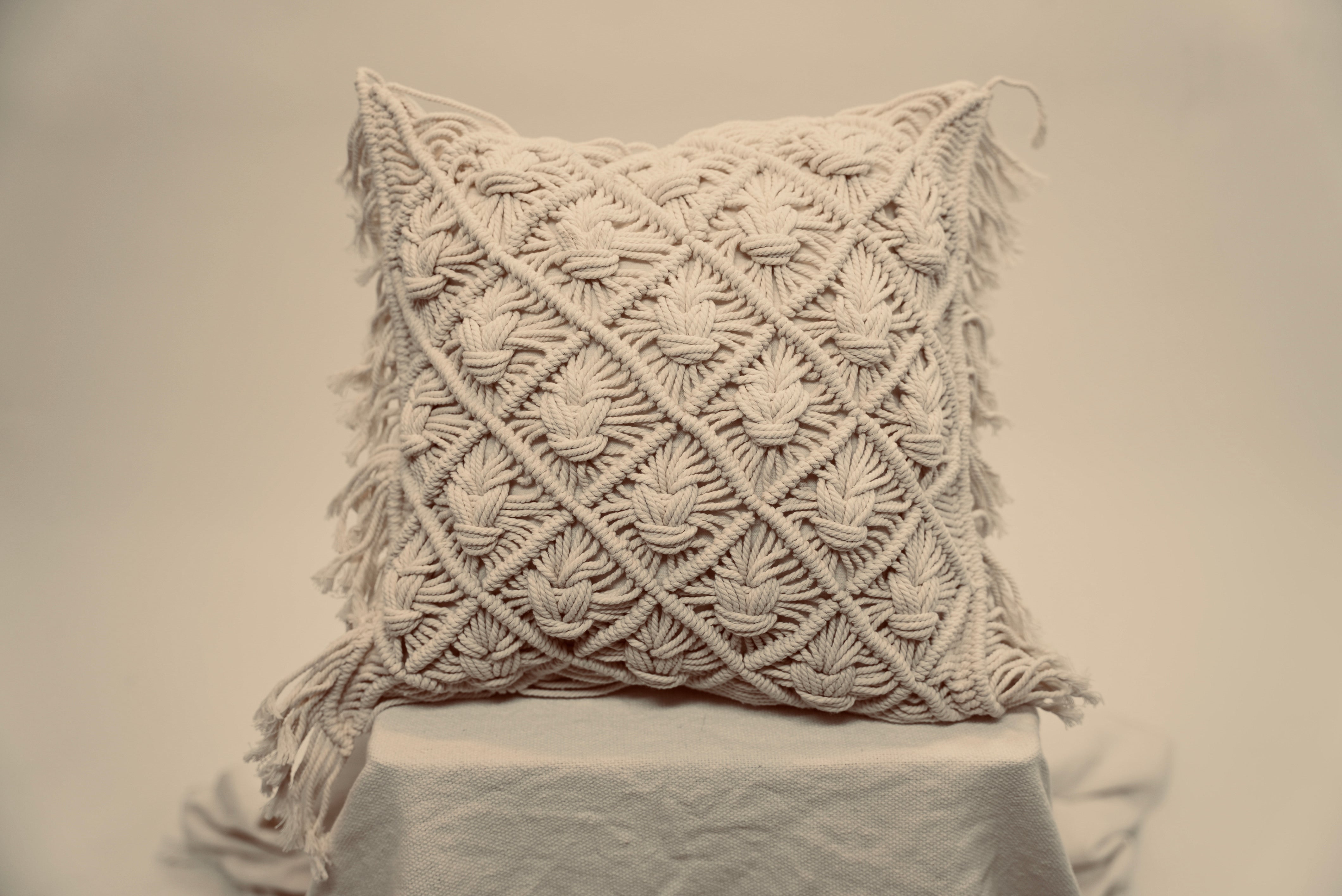 The macrame scatter cushions photographed against a neutral background