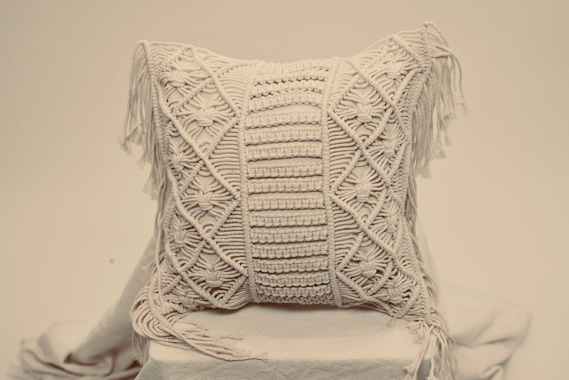 The macrame scatter cushions photographed against a neutral background