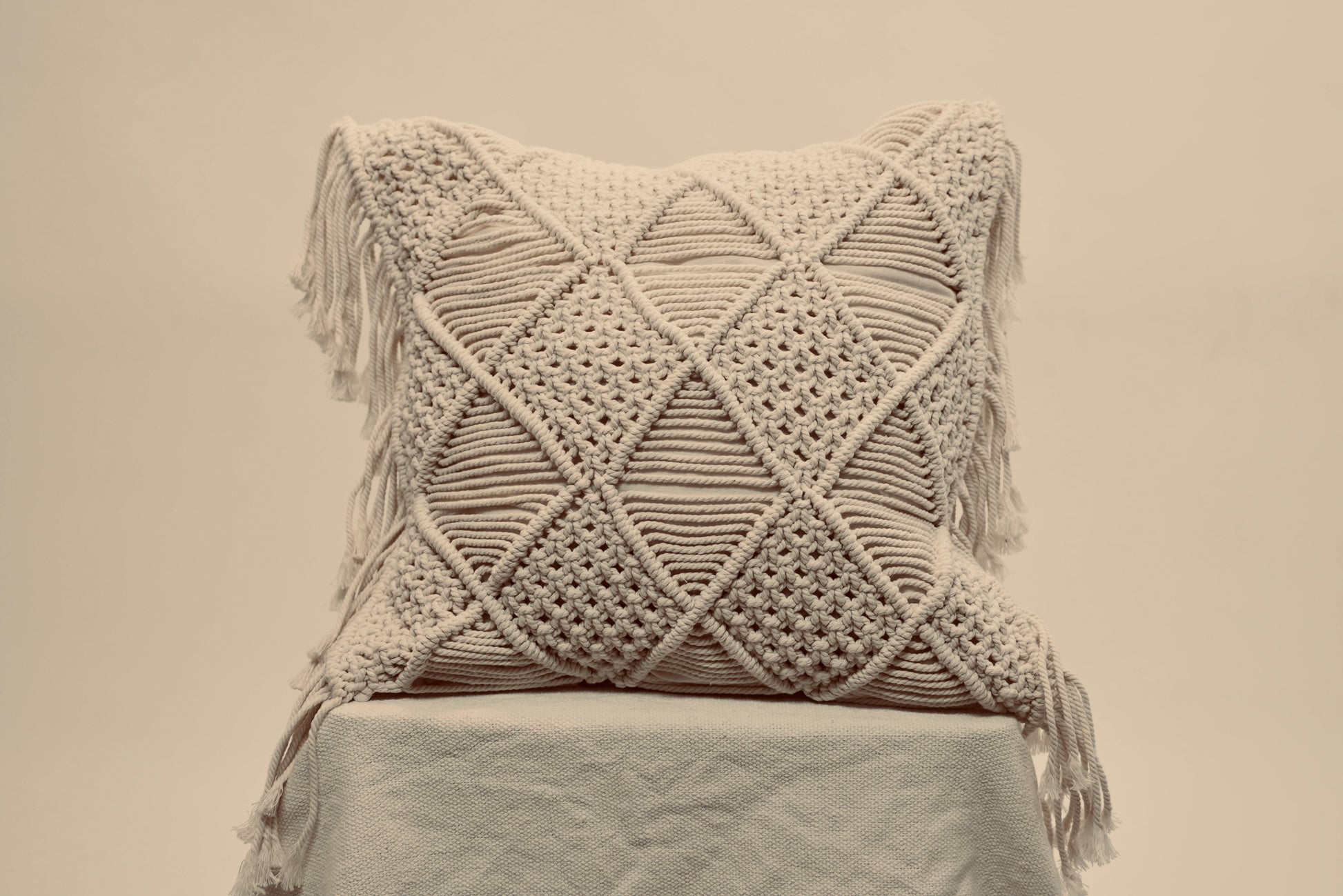 The macrame scatter cushions photographed against a neutral background