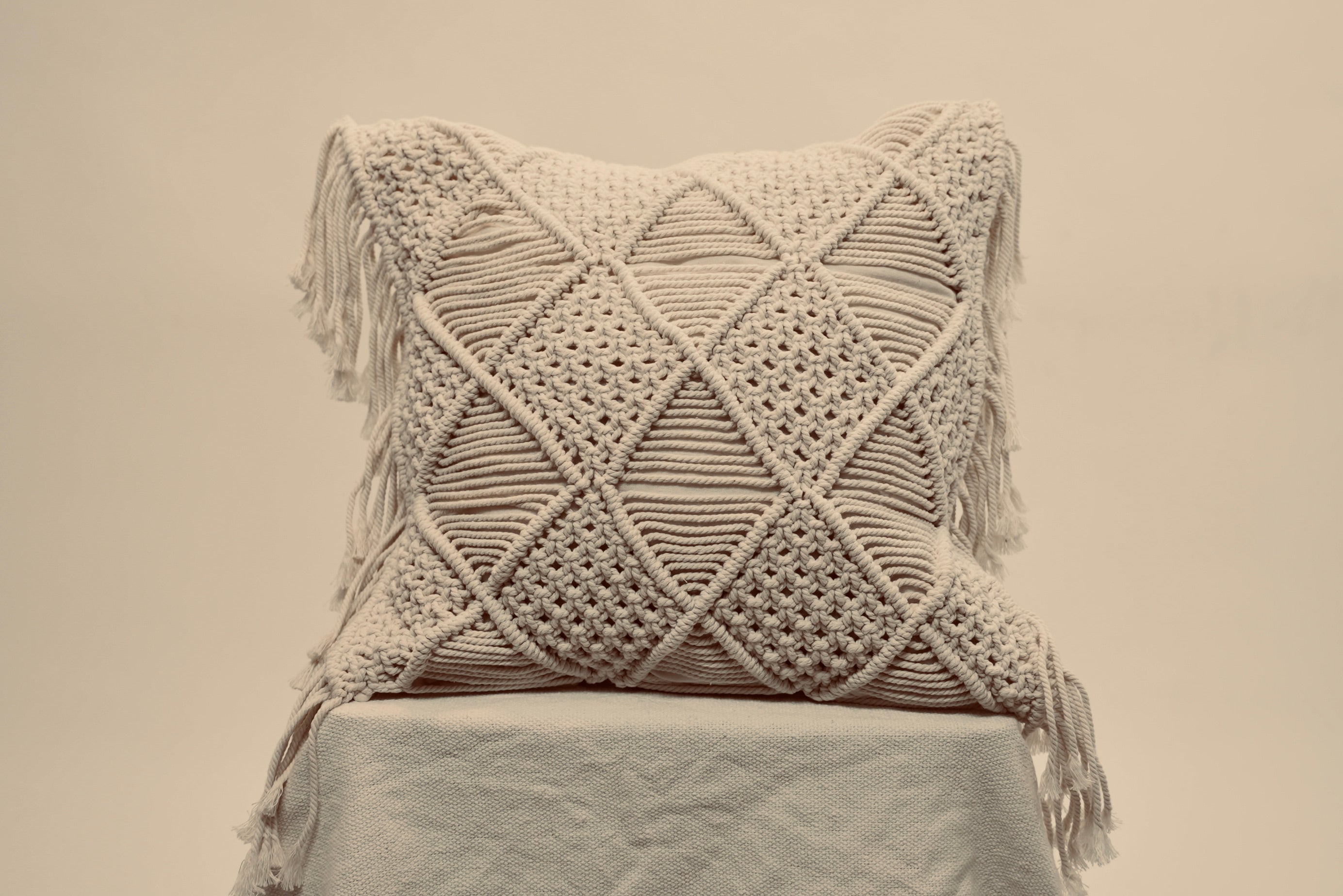The macrame scatter cushions photographed against a neutral background