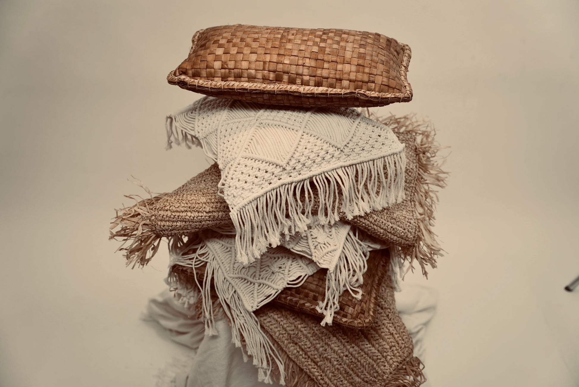 A stacked heap of cushions consisting of the Raffia cushion cover and our crispy woven cover as well