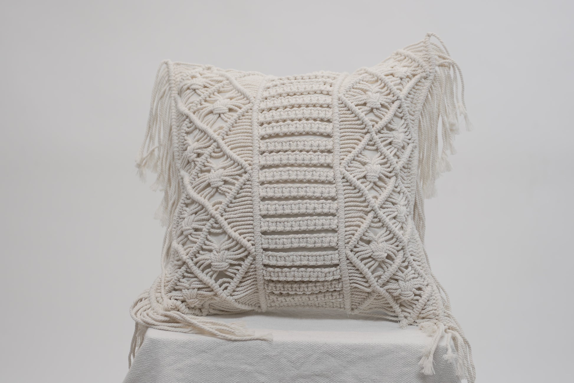 The macrame scatter cushions photographed against a neutral background