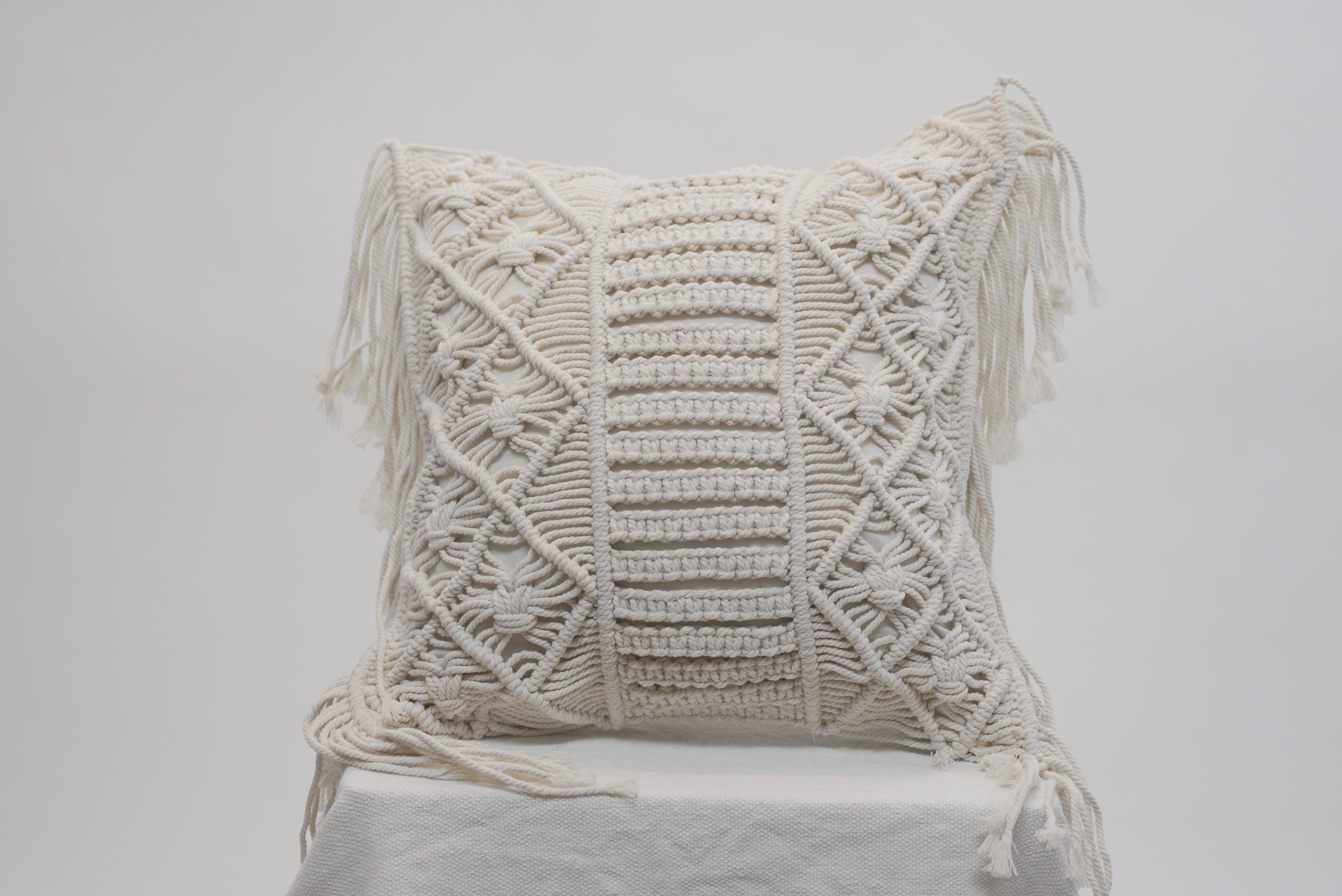 The macrame scatter cushions photographed against a neutral background