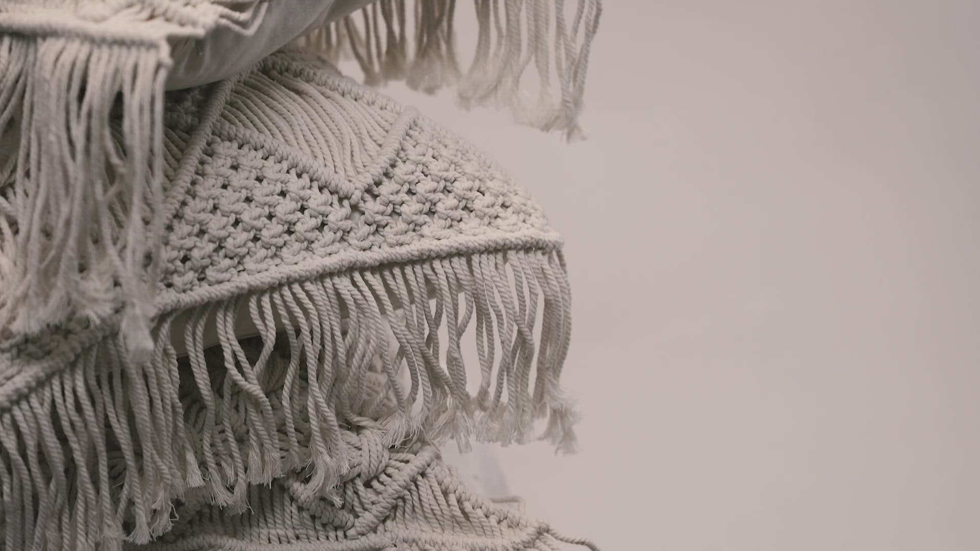 Load video: A close-up of the macrame scatter cushions photographed against a neutral background