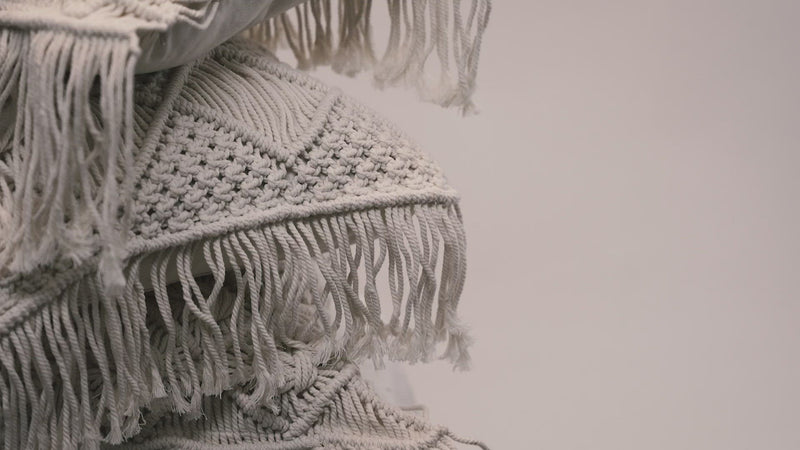 A close-up of the macrame scatter cushions photographed against a neutral background