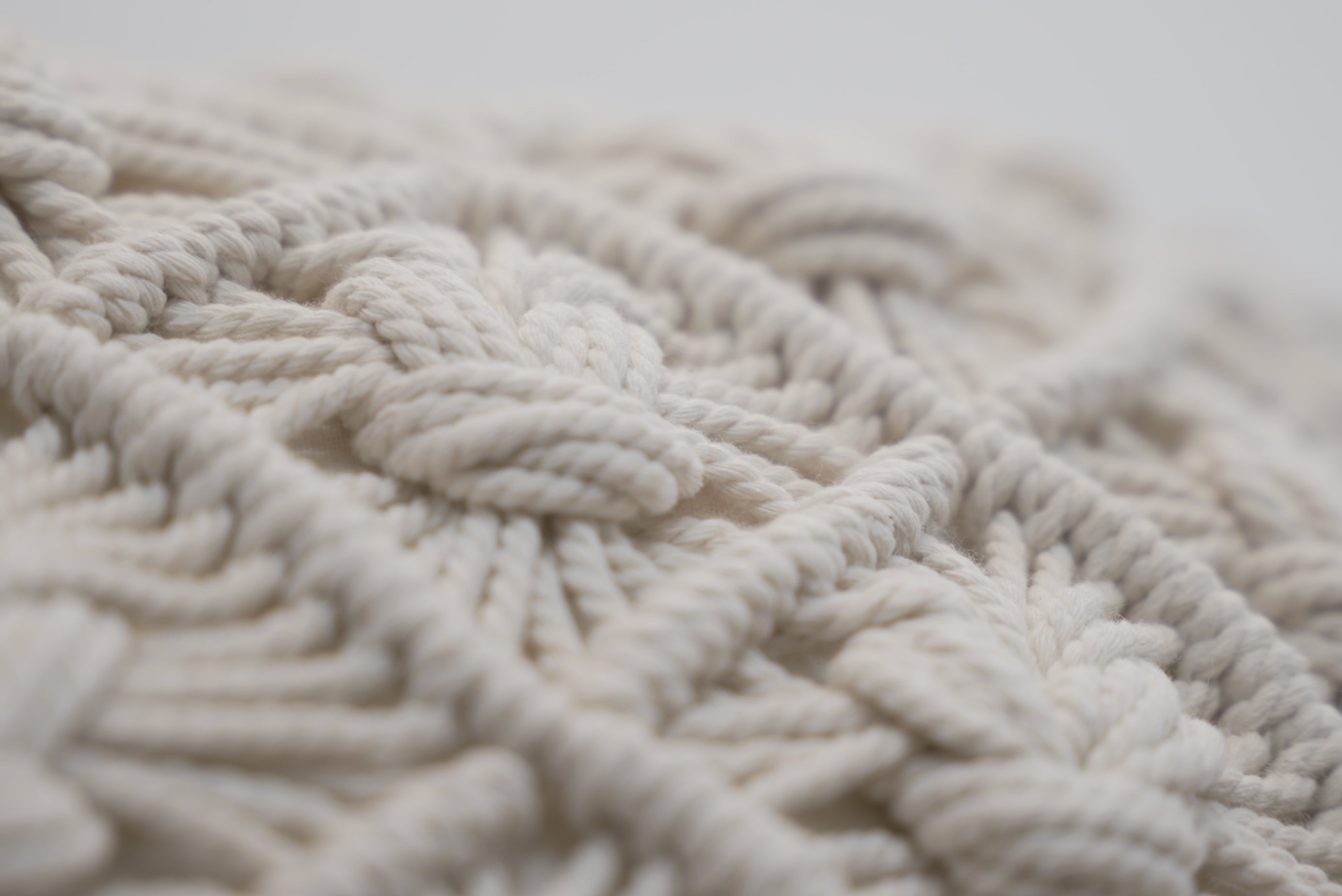 A close-up of the macrame scatter cushions photographed against a neutral background