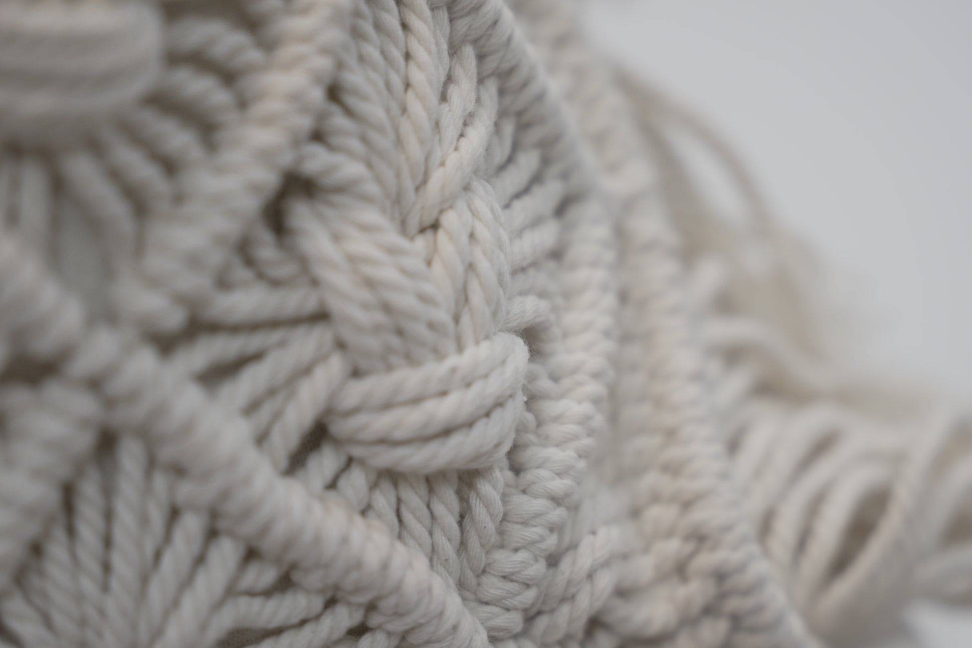 A close-up of the macrame scatter cushions photographed against a neutral background