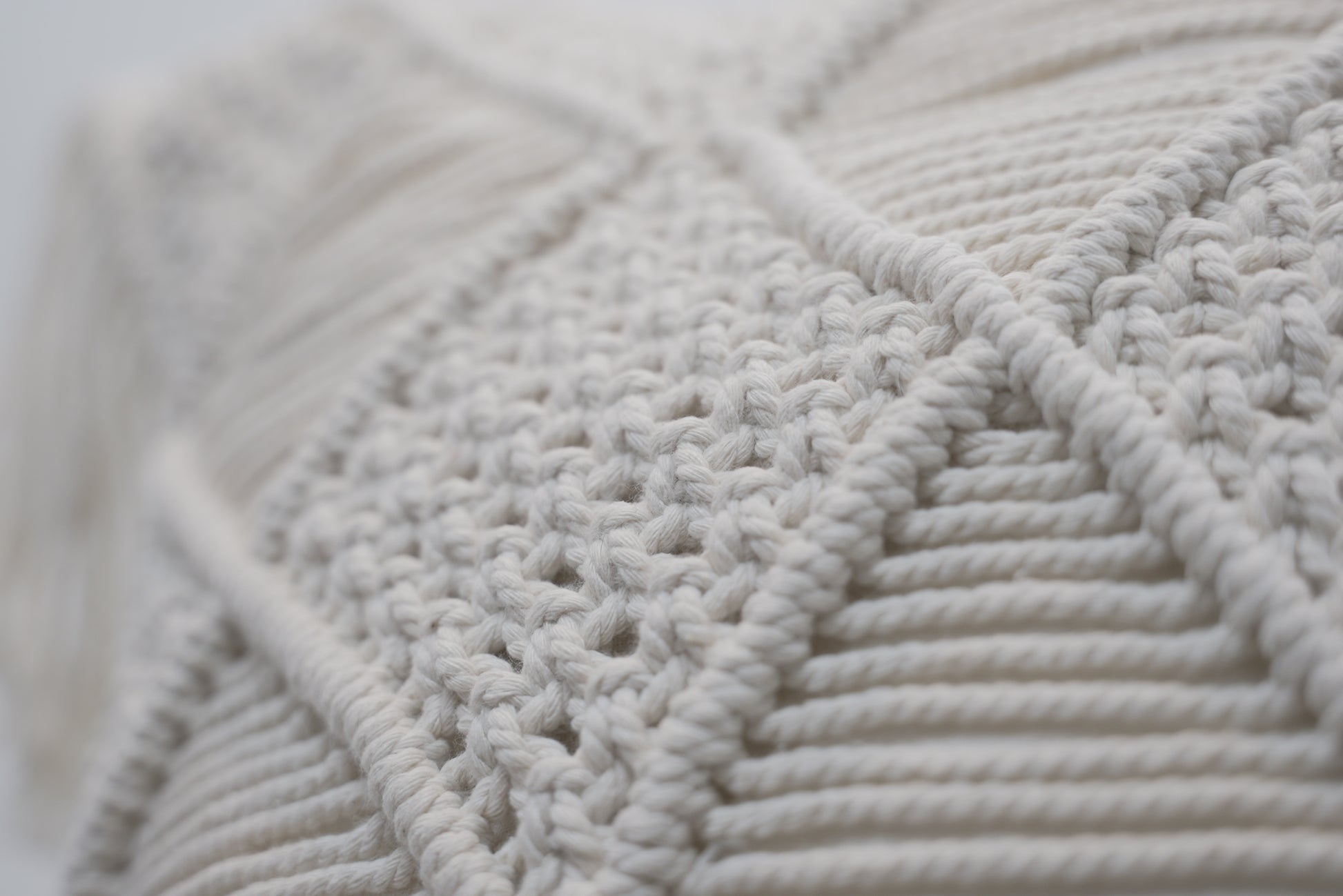 A close-up of the macrame scatter cushions photographed against a neutral background