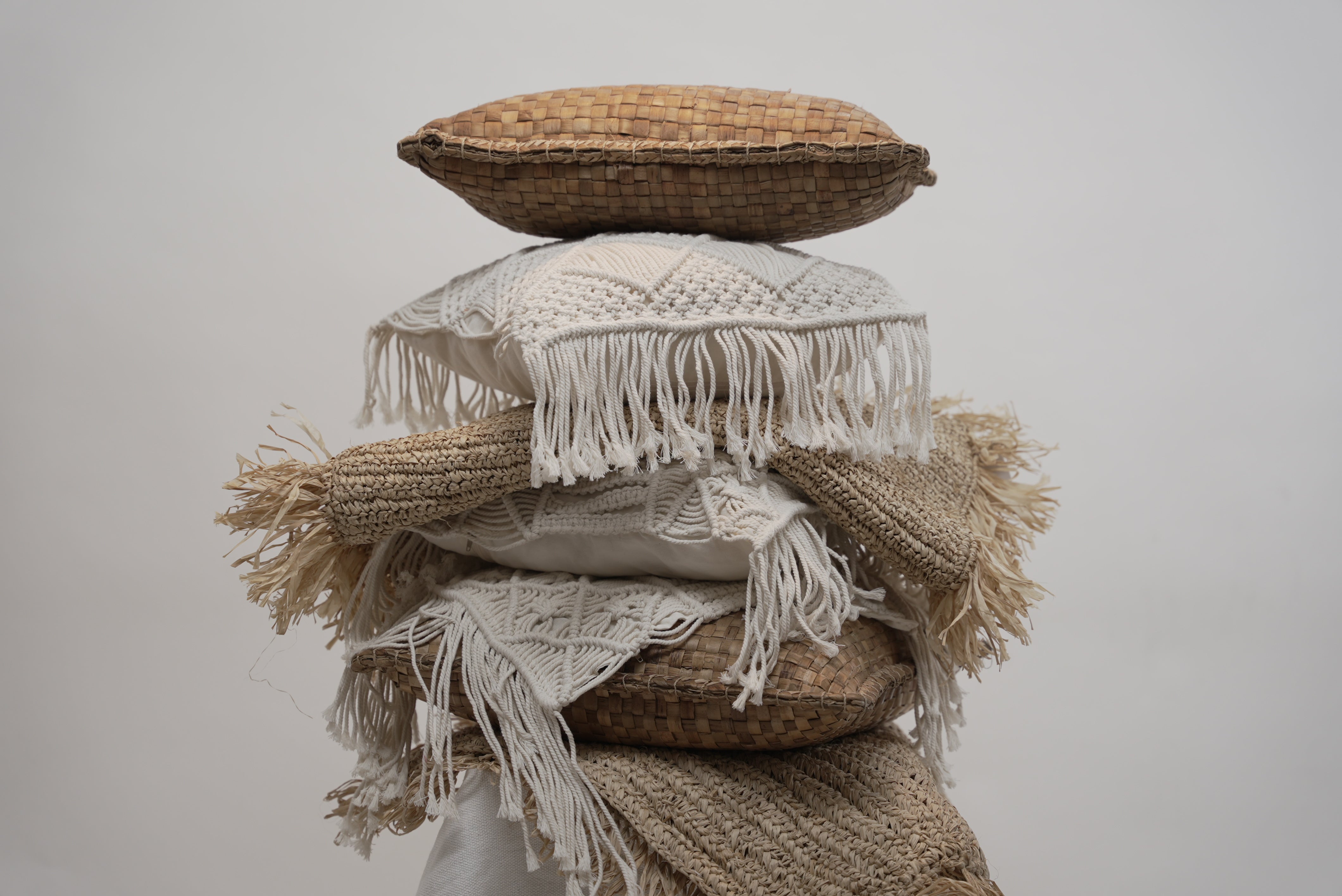 The crispy woven cushion photographed between other macrame cushions to showcase the contrast