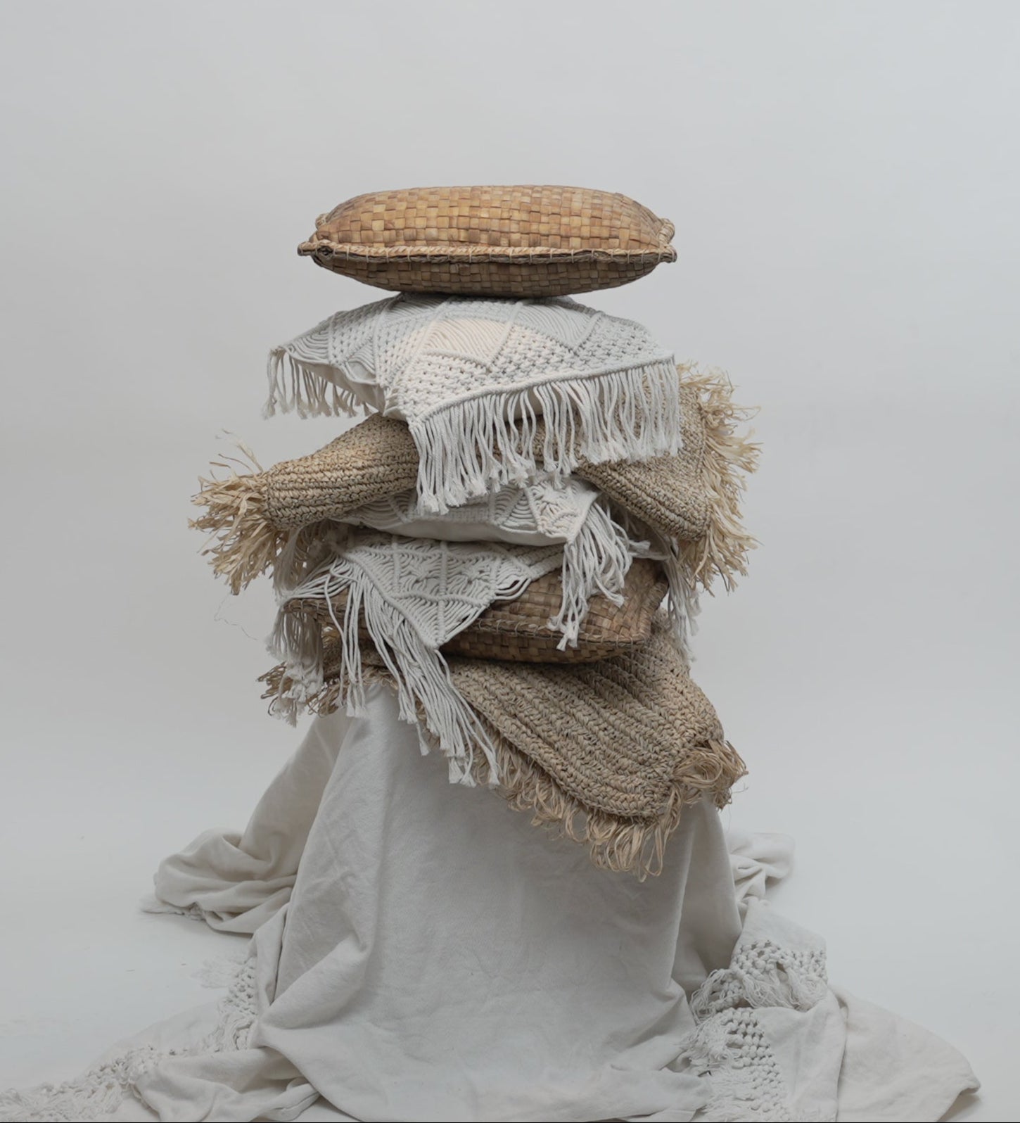 The crispy woven cushion photographed between other macrame cushions to showcase the contrast