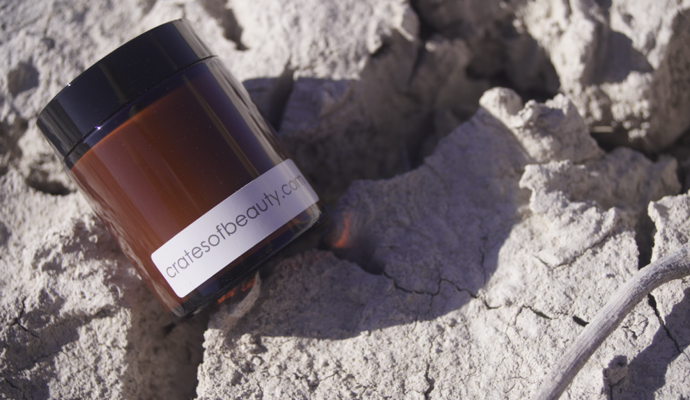 Close-up of soy candles in amber glass jars photographed outside on rocks