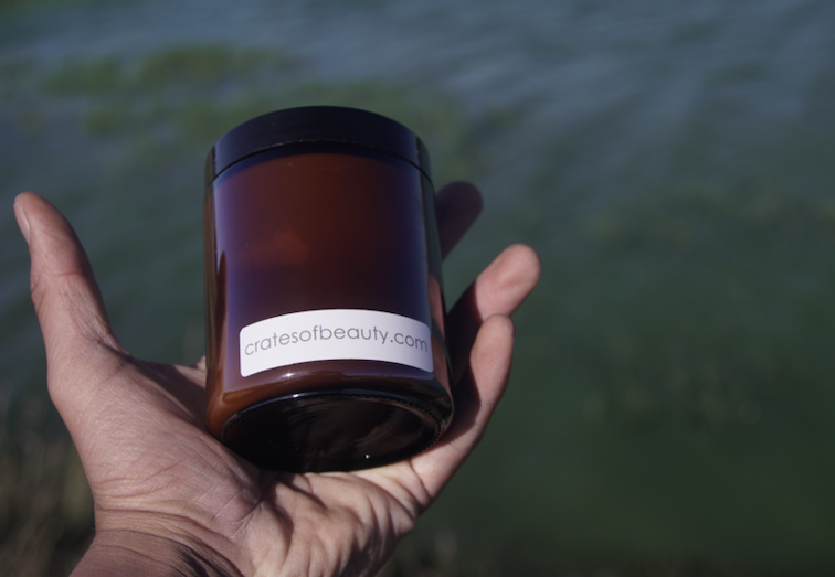 Soy candles in amber glass jar being held.