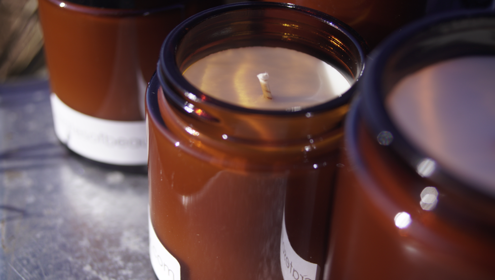 Close-up of soy candles in amber glass jars photographed outside
