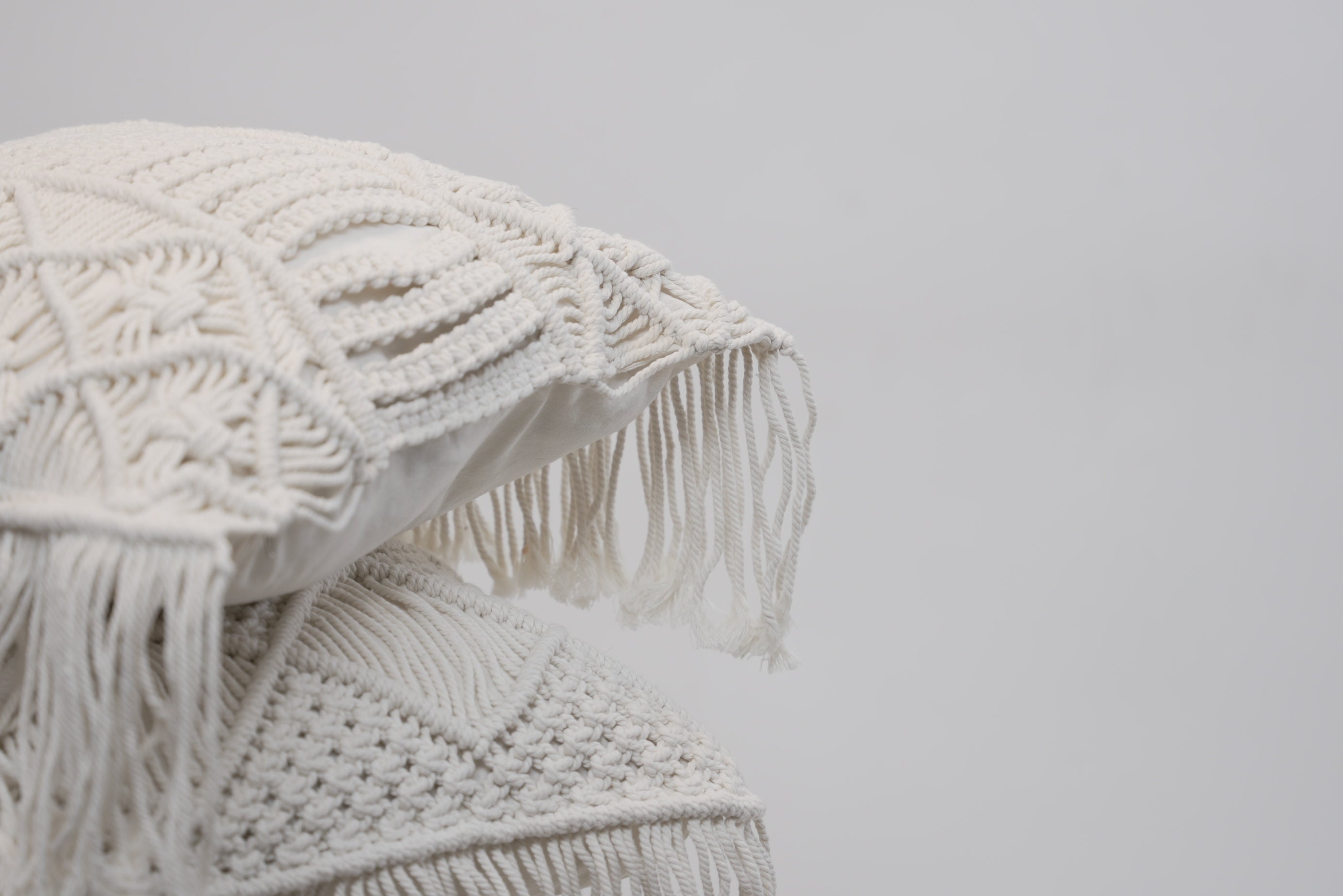 A close-up of the macrame scatter cushions photographed against a neutral background
